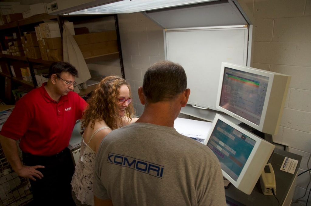 Prepress manager AJ and offset pressman Kevin meet with brand strategist Karen Chase to color check custom letterhead.